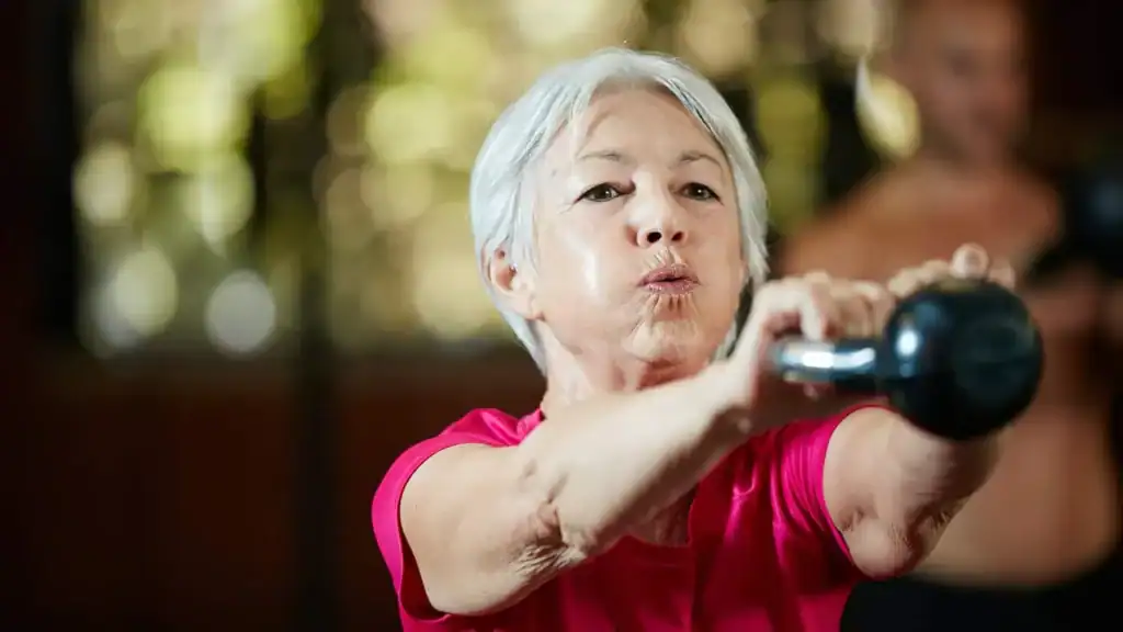 Older woman doing weight training Ashtead to help her strength and longevity 