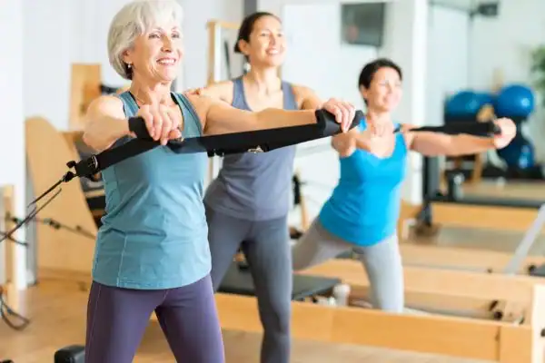 Toning Arms After 60: Empowering Womens Fitness Through Effective Weight Training 2 older woman doing weight training Ashtead and resistance in the gym to tone upper arms