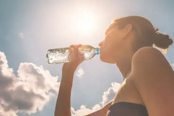 Hydration: The Secret Ingredient for a Toned Stomach and Enhanced Fitness 3 Image of woman drinking water to hydrate Ashtead after run.