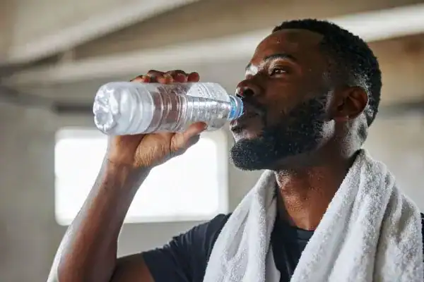 Image of man drinking water to improve hydration Ashtead after work out.